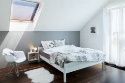 Białe meble w sypialni wyglądają lekko postawione na ciemnej podłodze