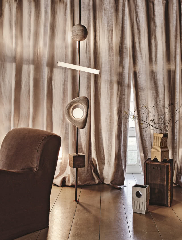 Beżowe zasłony w salonie z lampą podłogową w kształcie rzeźby