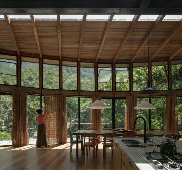 salon z kuchnią w kształcie elipsy, kobieta zasuwa zasłony