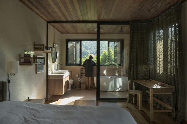 kobieta w łazience, przeszklone drzwi, na pierwszym planie łóżko